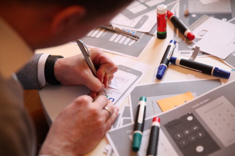 Design Thinking: Person fertig Skizzen für App auf Papier an